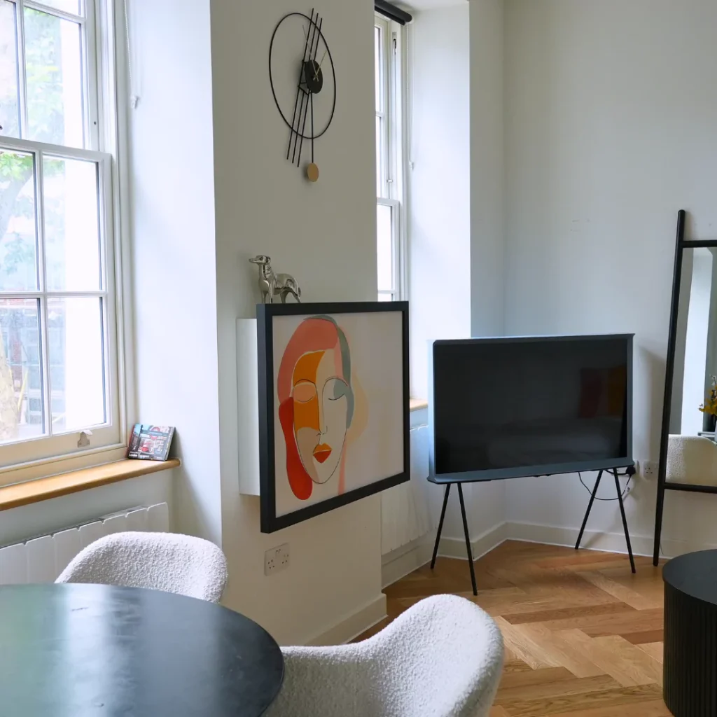 DropTop desk closed, styled as framed artwork beside a window in a living space.