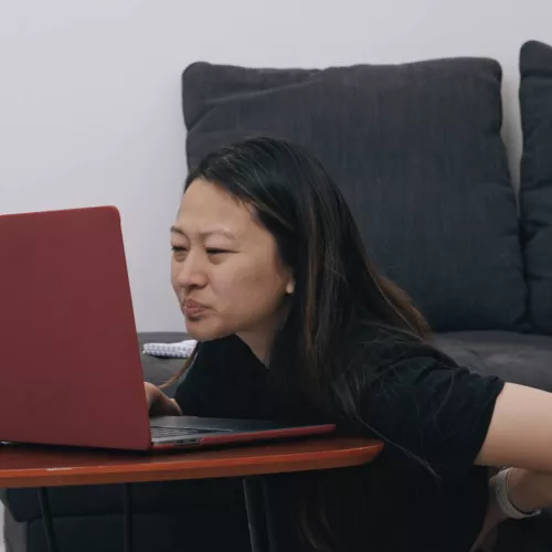 Person leaning forward at a laptop with poor posture, suggesting back strain while working.