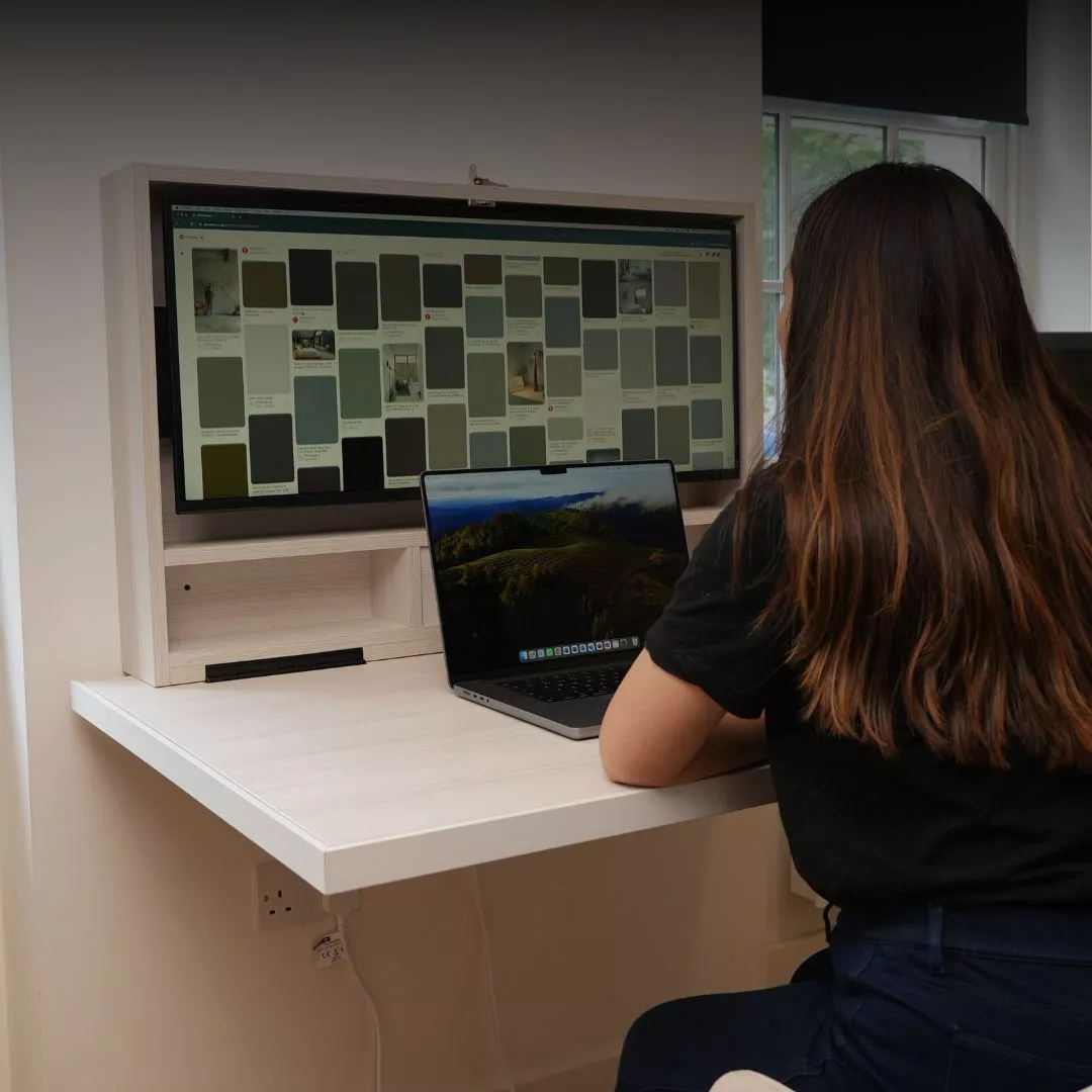 Person working at an open DropTop desk with laptop and monitor.