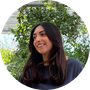 Profile photo of woman with long dark hair looking to the side outdoors