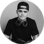 Black and white headshot of man wearing cap and headphones around neck