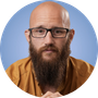 Headshot of man with glasses and long beard against blue background