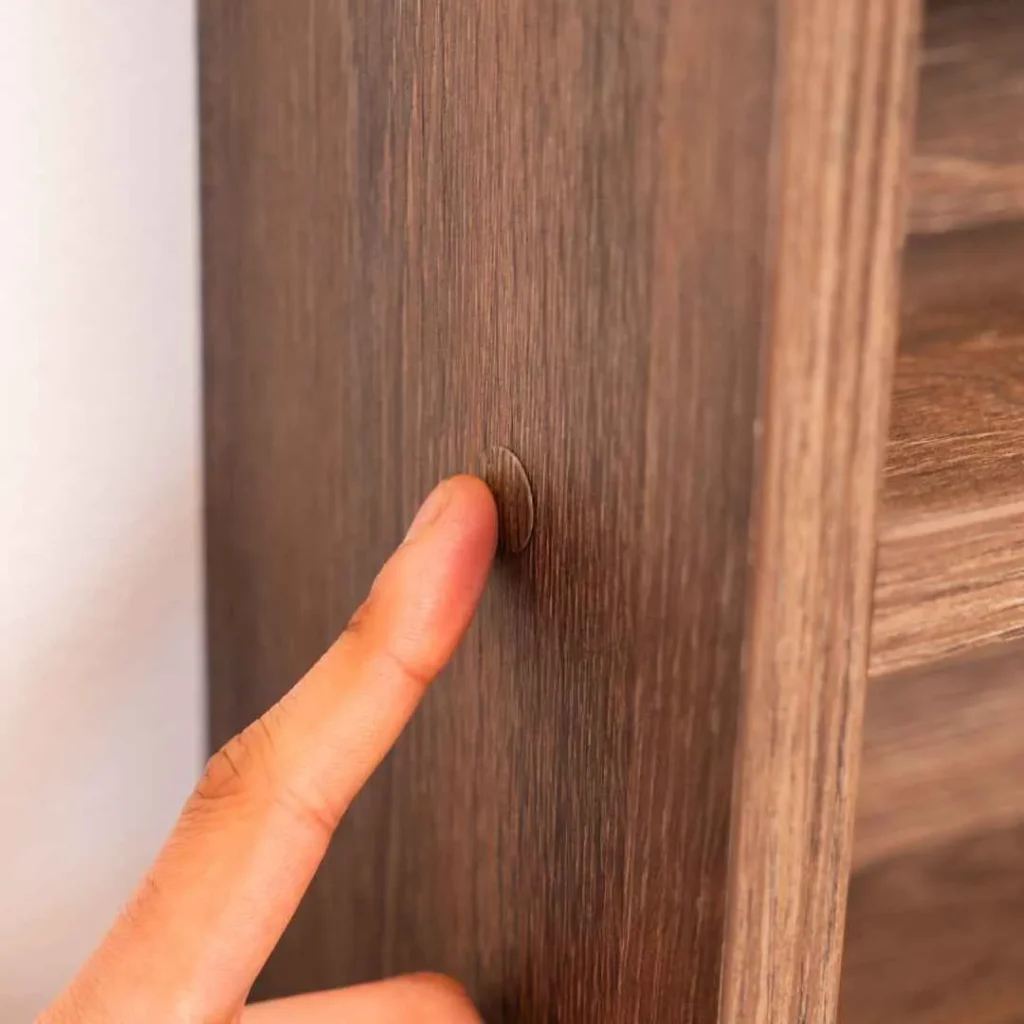 Close up of screw cover sticker blending seamlessly into wood grain desk finish