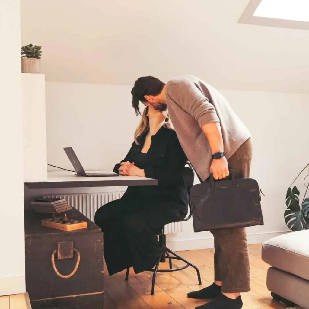 Person greeting someone at an open DropTop desk with laptop setup.