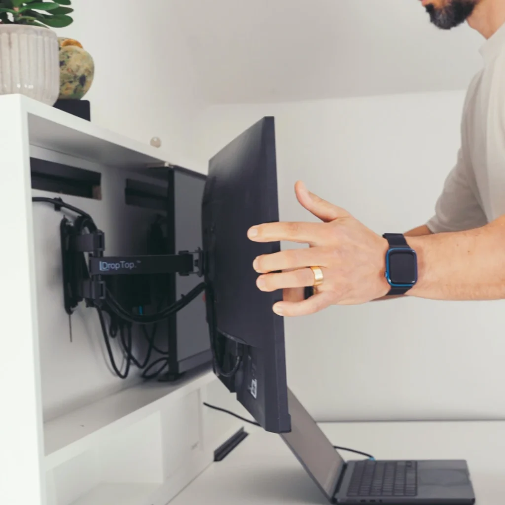 Person adjusting a monitor on an extendable wall-mounted monitor arm.