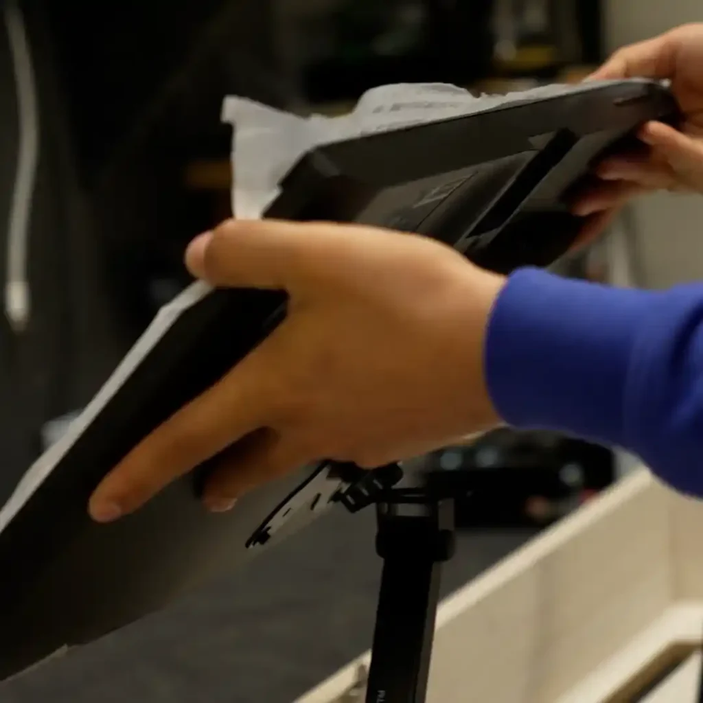 Hands positioning a monitor onto a mounting bracket for a floating desk system