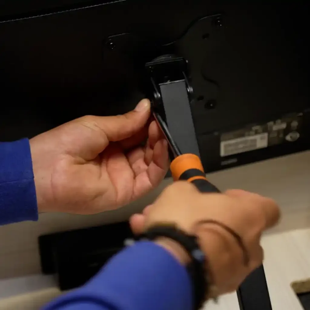 Installing a monitor mount bracket onto a screen as part of a wall desk setup process
