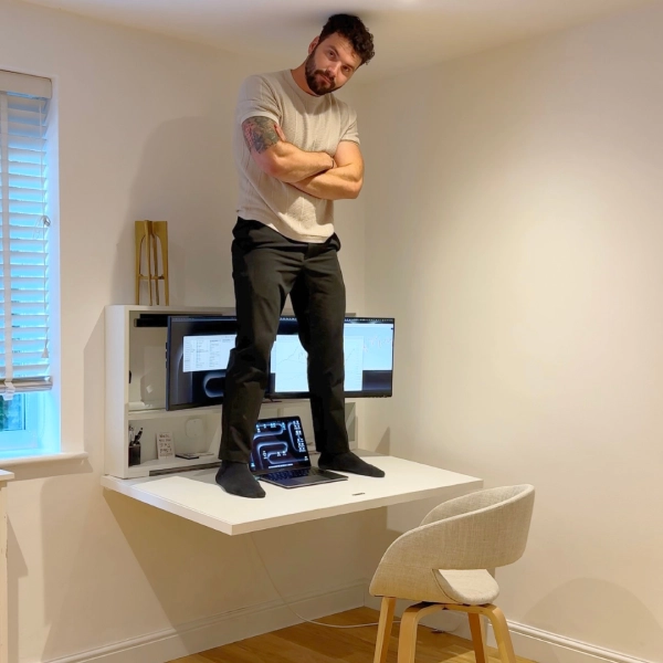 DropTop floating desk demonstrating strength with man standing on wall mounted folding desk in space saving setup