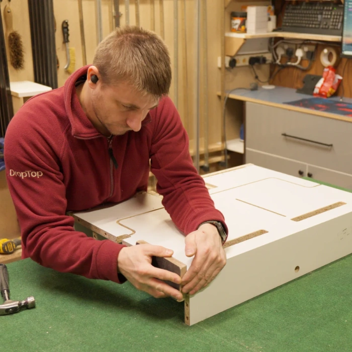 Wall-Mounted Folding Desks for Home Offices DropTop floating desk unit being assembled by hand showing compact folding desk craftsmanship in workshop.