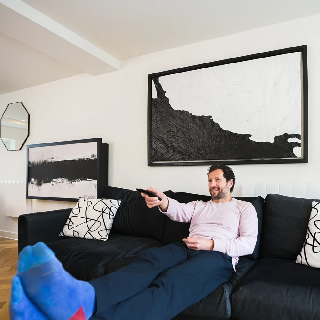 Concealed wall desk styled as abstract artwork above sofa in modern living room with minimalist design
