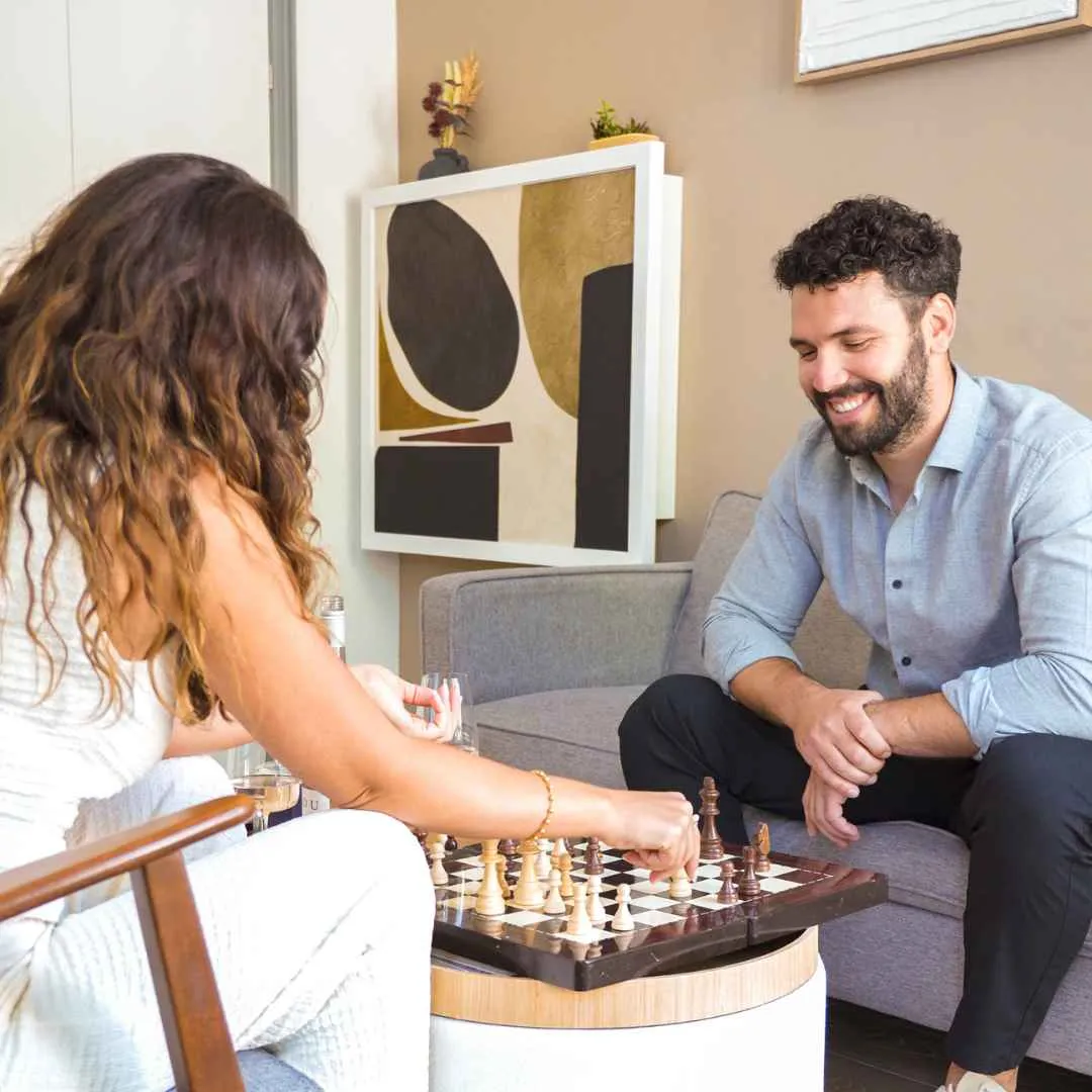 Wall-Mounted Folding Desks for Home Offices A couple playing chess on their coffee table with their Murphy desk in the background.