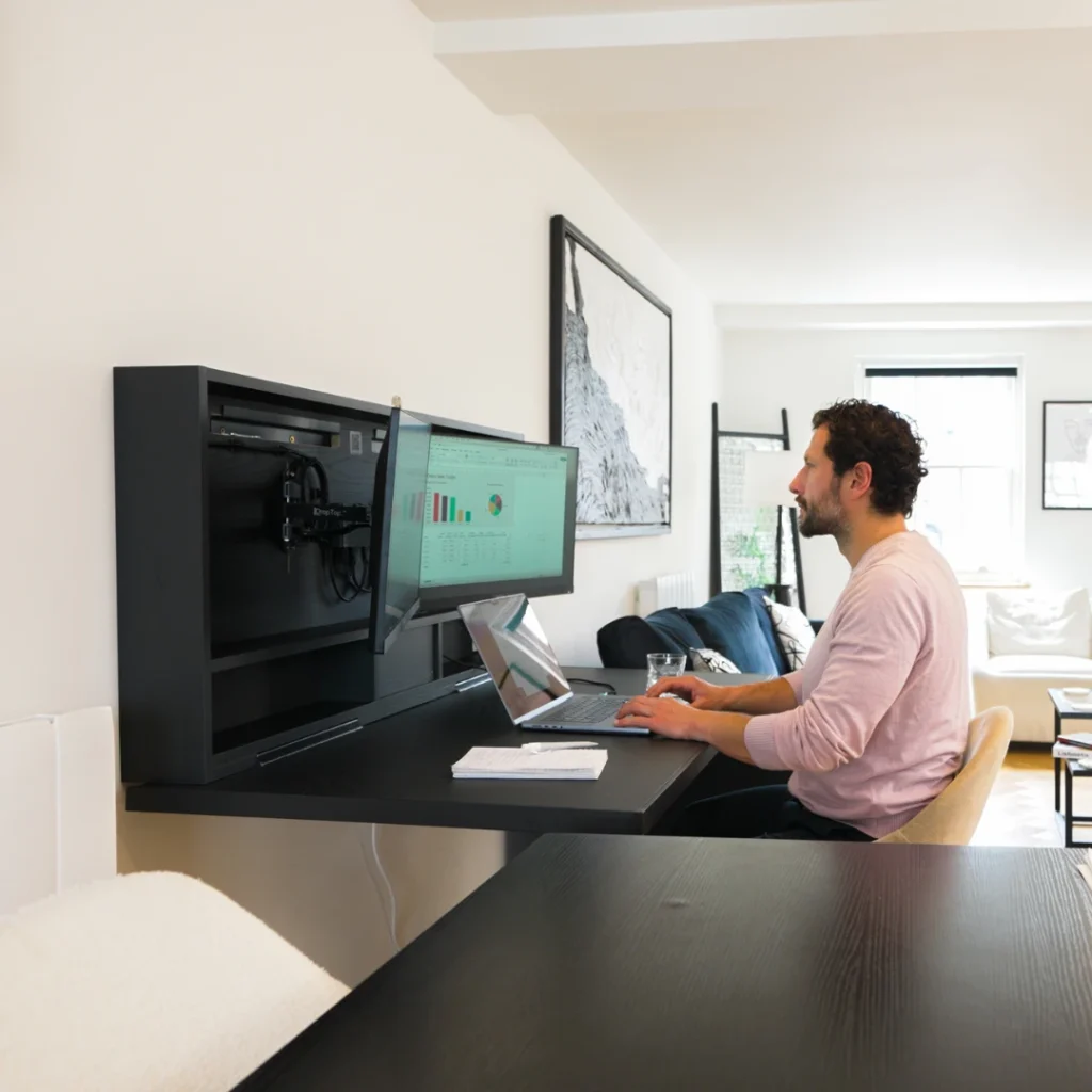 Wall integrated desk with monitor and laptop in use by a remote worker