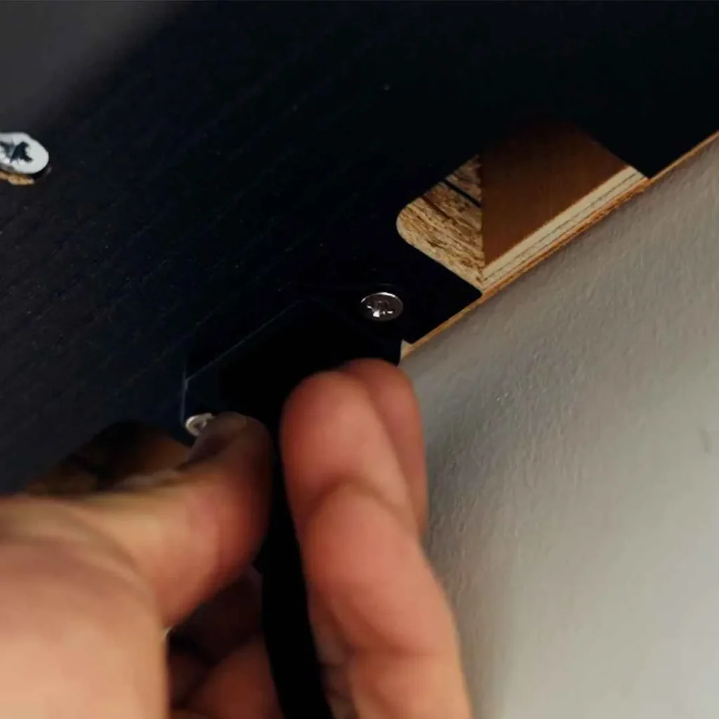 Hand connecting a single cable to the underside port of a DropTop desk.