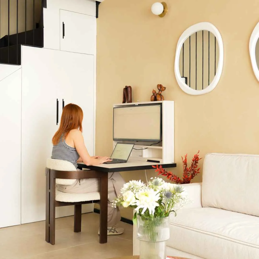 A woman working at an open DropTop desk with a large screen in a stunning interior.